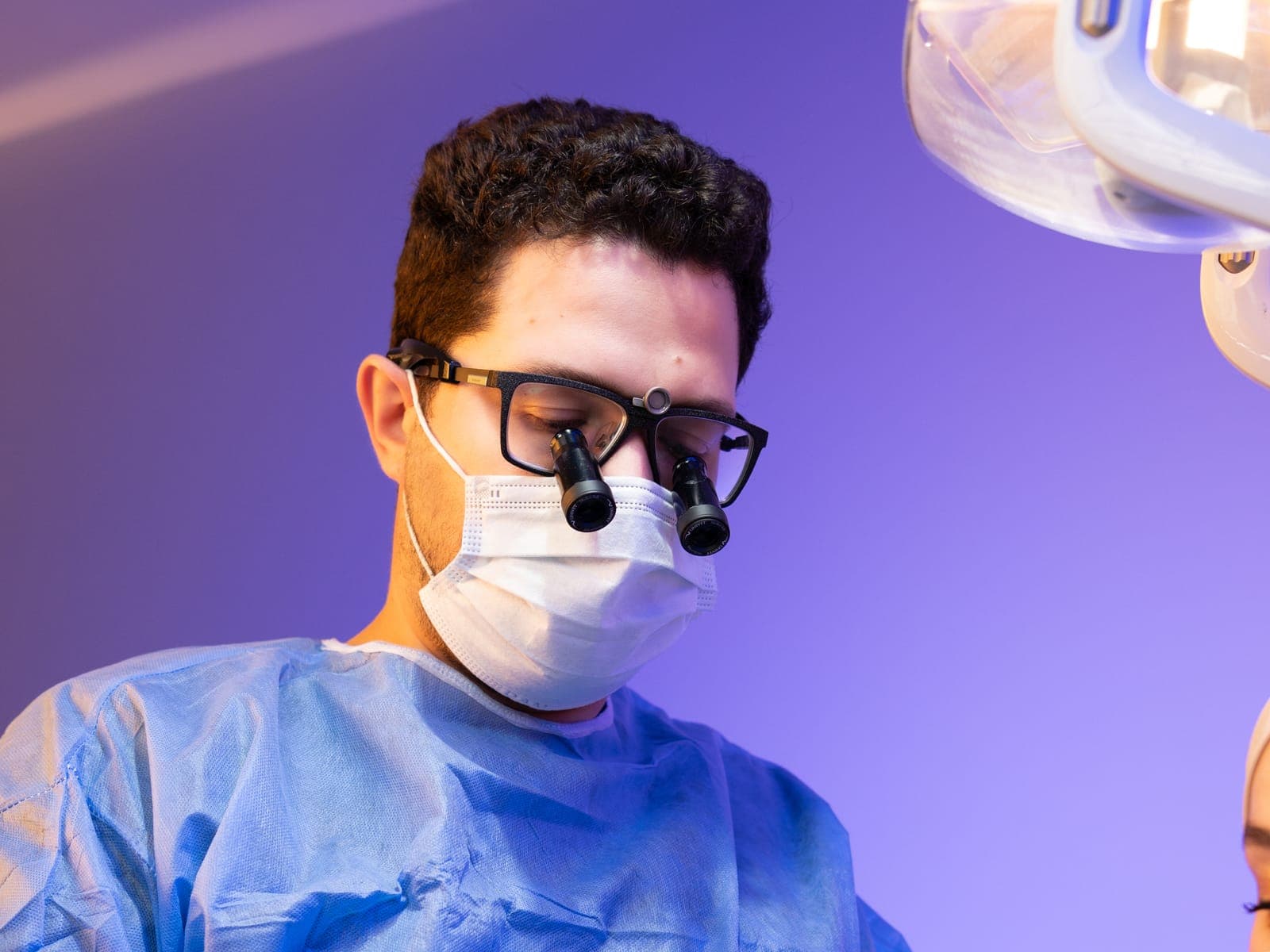 Un chirurgien-dentiste équipé de loupes de grossissement pendant une intervention