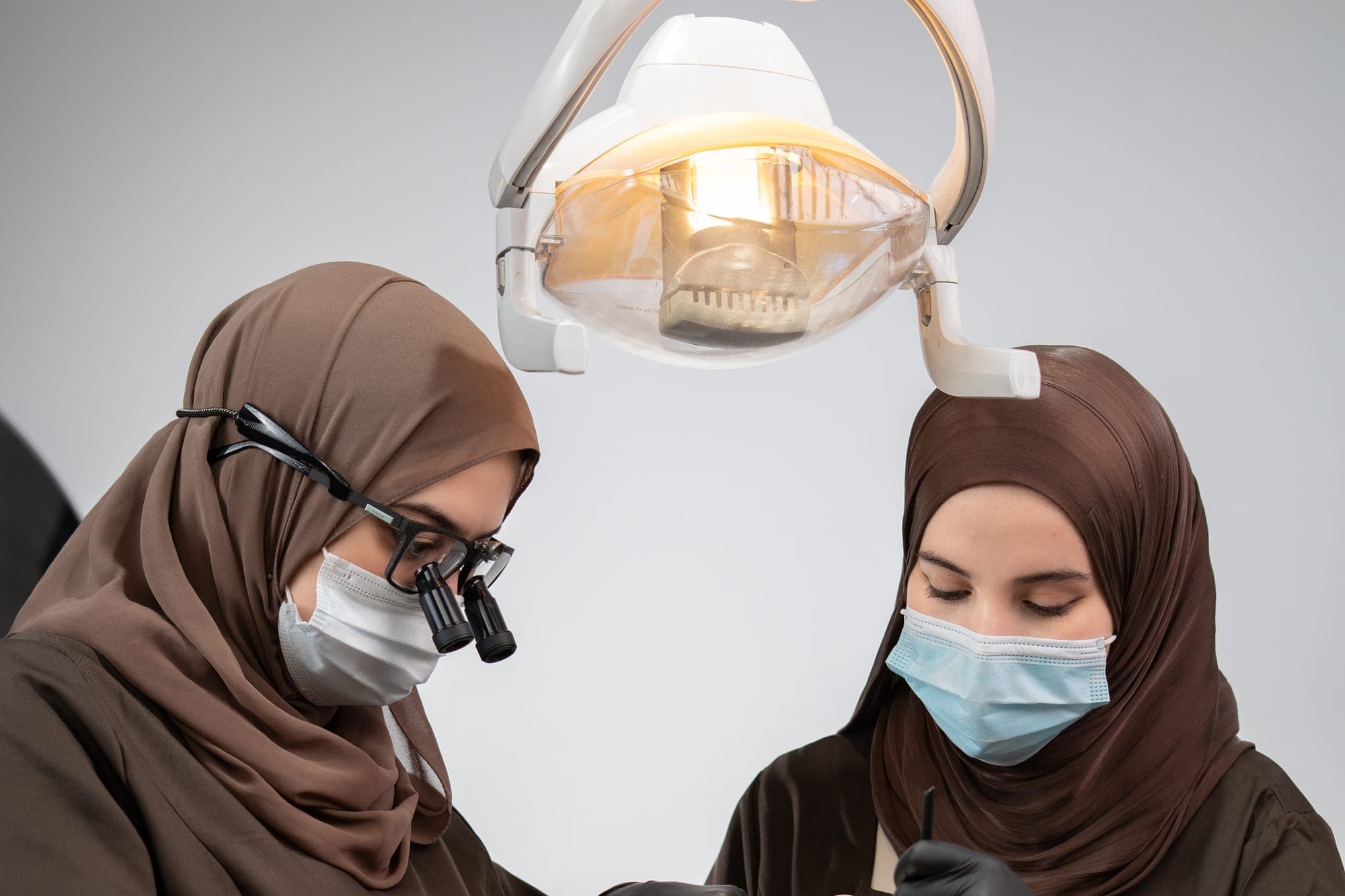 Deux praticiennes au travail sous la lampe opératoire