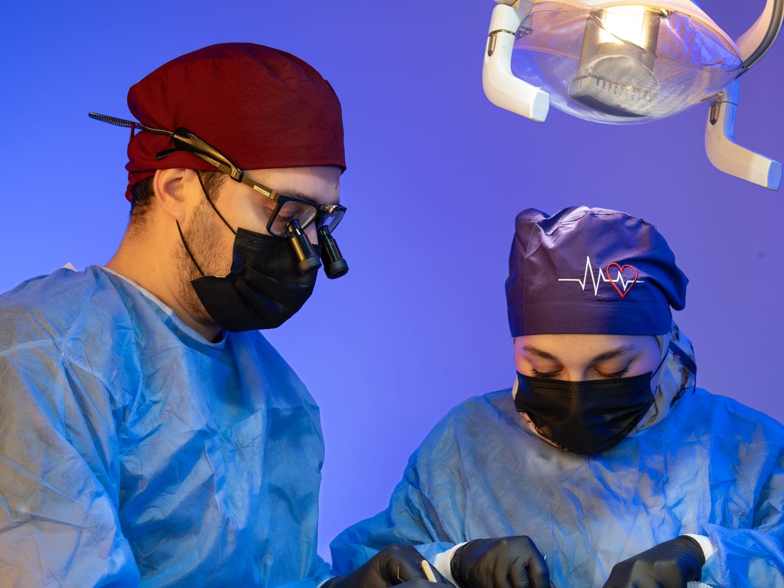 Deux praticiens en blouse chirurgicale, masque et calot pendant un acte