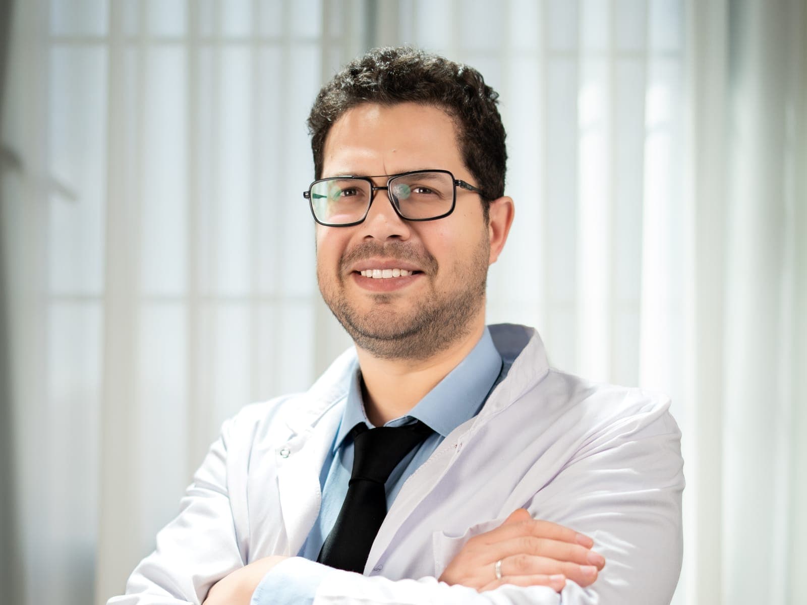 Un chirurgien-dentiste en blouse blanche, bras croisés, dans une salle lumineuse